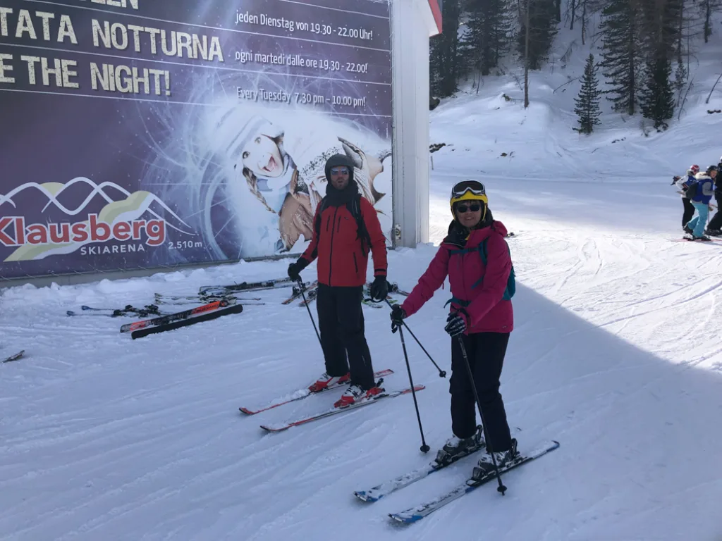 Zwei Personen stehen vor einer Werbetafel an der Piste.